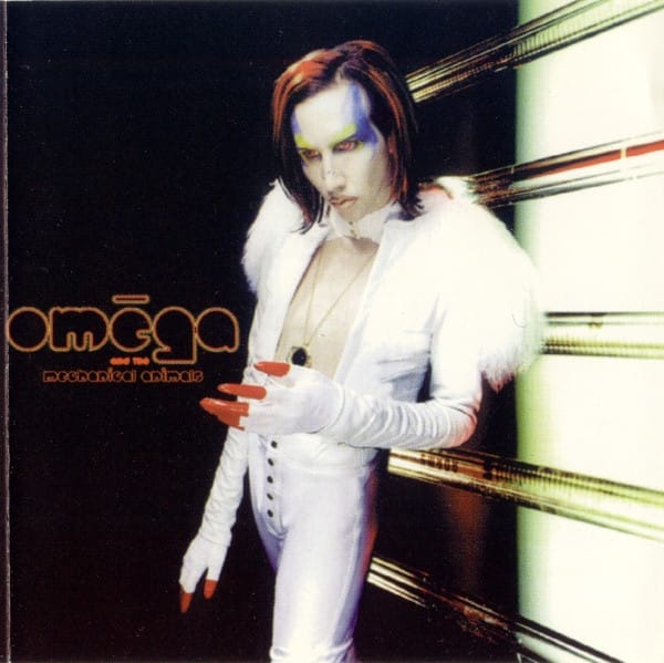 Marilyn Manson as Omega, seated in a gold outfit with a cutout at the chest revealing the plain wall behind him, posing as the cover for the fictional band Omega and the Mechanical Animals.