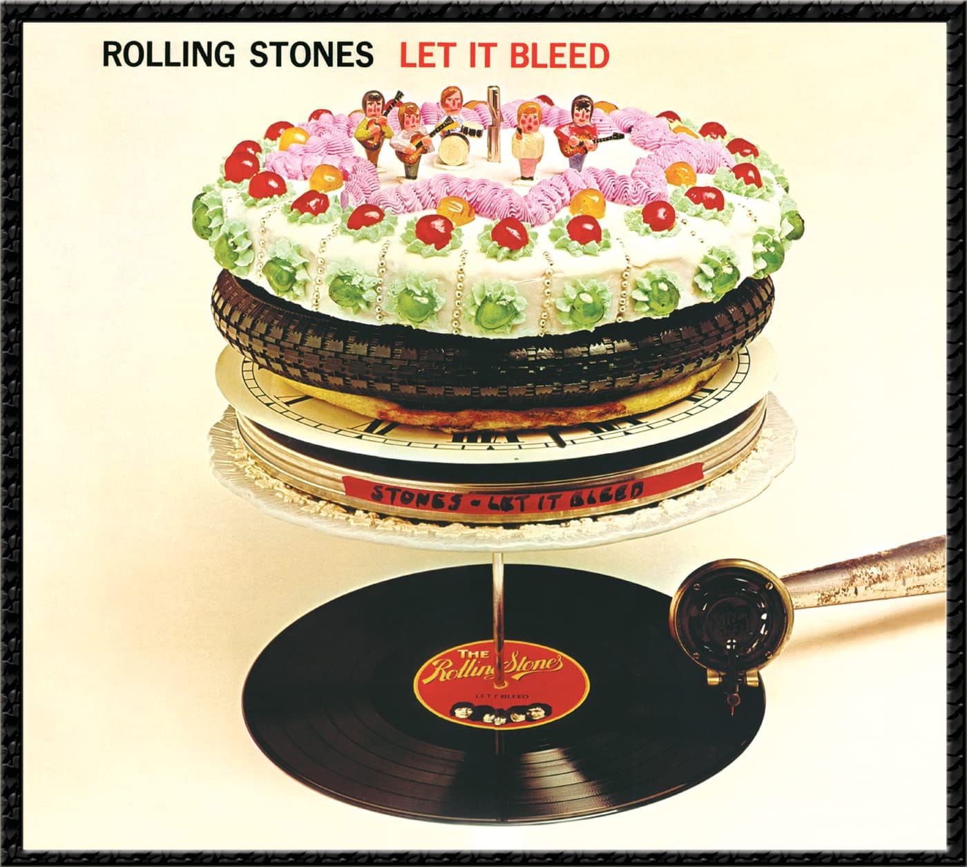 Front cover of The Rolling Stones’ 1969 album Let It Bleed, featuring Robert Brownjohn’s surreal sculpture of an antique record‑changer spindle stacked with a film canister, clock face, pizza, bicycle tyre, and a gaudy cake topped by miniature figurines of the band, photographed by Don McAllester with the cake baked by Delia Smith.