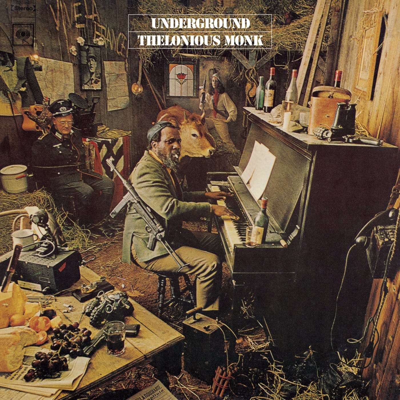 Front cover of Thelonious Monk’s 1968 Columbia album Underground, depicting Monk as a fictional French Resistance fighter at an upright piano with a machine gun slung over his shoulder, surrounded by wartime props and a tied‑up Nazi soldier in a staged attic set photographed by Horn/Griner Studios.