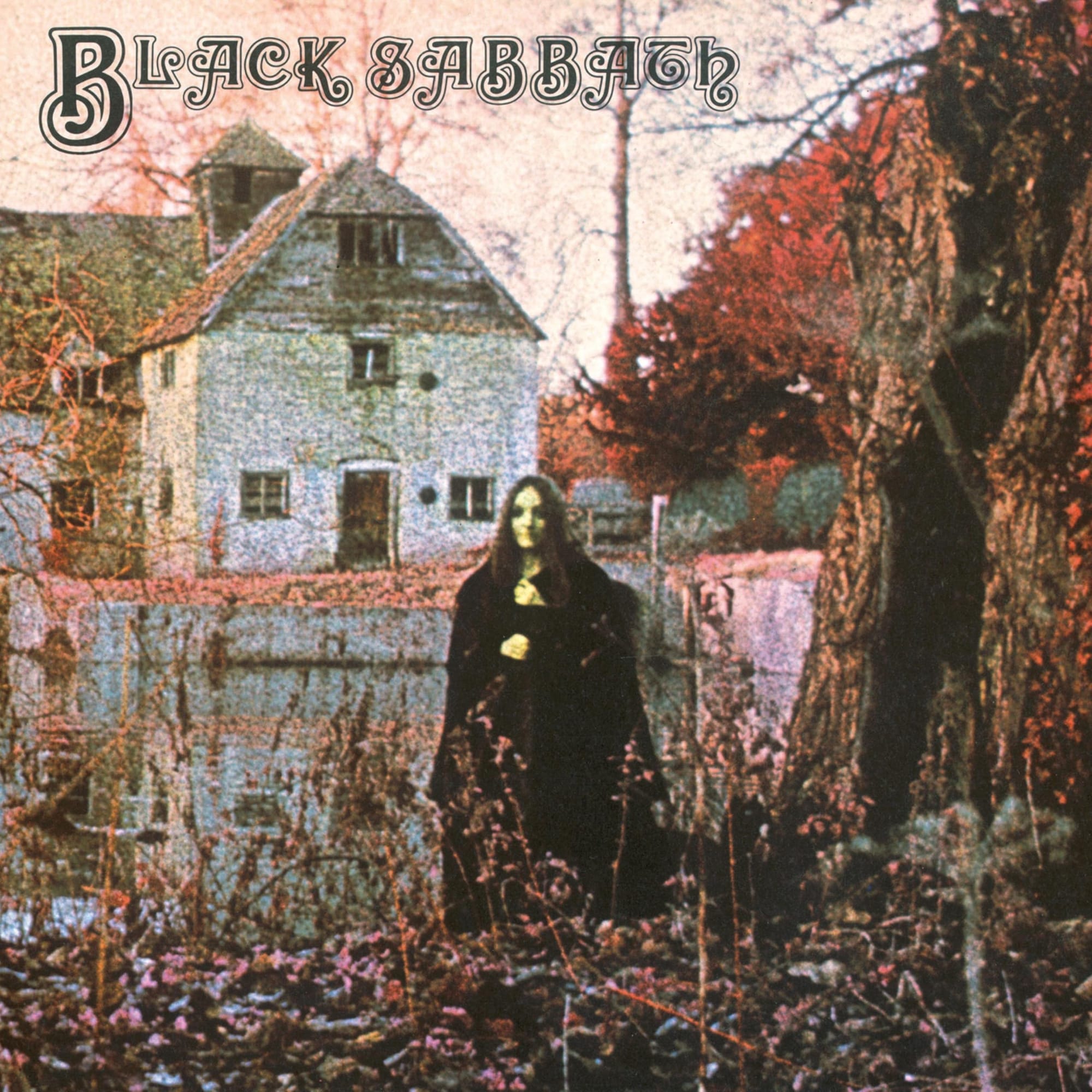 Black-robed figure in front of an old watermill, on pink-toned infrared film, on Black Sabbath's debut album cover.