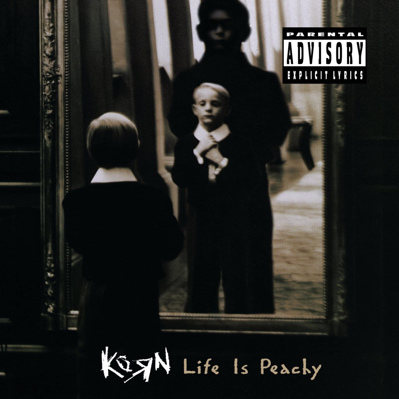 Black-and-white photo of a small boy adjusting his tie in a gilt mirror, a huge shadow behind him, on Korn's Life Is Peachy.